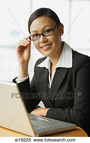 Businesswoman sitting in front of laptop, smiling at camera, portrait View Large Photo Image Stock Photography - Businesswoman sitting in front of laptop, smiling at camera, portrait. Fotosearch