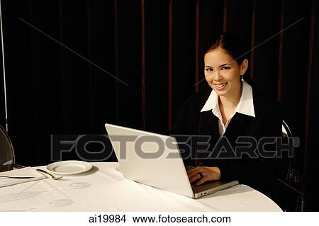Businesswoman sitting in restaurant using laptop, smiling View Large Photo Image Picture - Businesswoman sitting in restaurant using laptop, smiling. Fotosearch