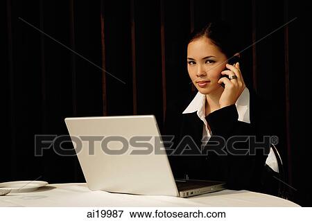Businesswoman sitting in restaurant using mobile phone and laptop, looking at camera View Large Photo Image Stock Photo - Businesswoman sitting in restaurant using mobile phone and laptop, looking at camera. Fotosearch