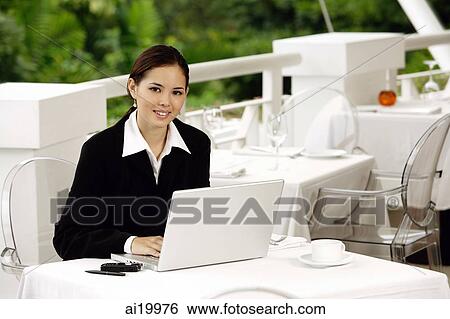Businesswoman sitting in restaurant with laptop, looking at camera View Large Photo Image Stock Photograph - Businesswoman sitting in restaurant with laptop, looking at camera. Fotosearch