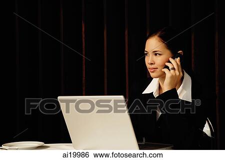 Businesswoman sitting in restaurant using mobile phone and laptop View Large Photo Image Stock Photograph - Businesswoman sitting in restaurant using mobile phone and laptop. Fotosearch