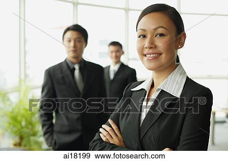 Businesswoman smiling at camera, two businessman in the background View Large Photo Image Stock Photo - Businesswoman smiling at camera, two businessman in the background. Fotosearch