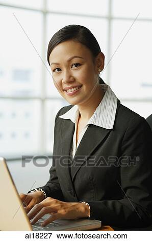 Businesswoman using laptop, looking at camera View Large Photo Image Stock Photo - Businesswoman using laptop, looking at camera. Fotosearch