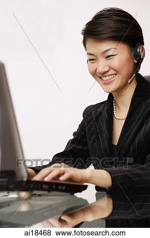 Businesswoman using laptop, using hands free device View Large Photo Image Stock Photo - Businesswoman using laptop, using hands free device. Fotosearch