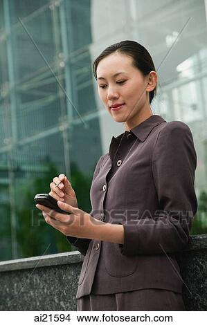 Businesswoman using PDA, city location View Large Photo Image Picture - Businesswoman using PDA, city location. Fotosearch