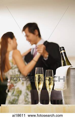 Champagne glasses and bottle in foreground, couple dancing in background View Large Photo Image Stock Image - Champagne glasses and bottle in foreground, couple dancing in background. Fotosearch