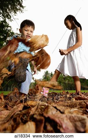 Children kicking leaves in park View Large Photo Image Picture - Children kicking leaves in park. Fotosearch