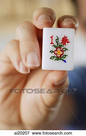 Stock Photo - Close-up of hand holding mahjong tile with the Chinese script for Spring. Fotosearch