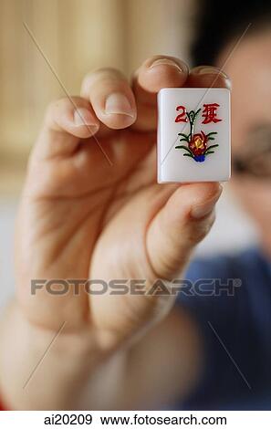 Stock Photo - Close-up of hand holding mahjong tile with the Chinese script for Summer. Fotosearch
