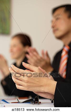 Stock Image - Close-up of woman's hands clapping, people in the background. Fotosearch