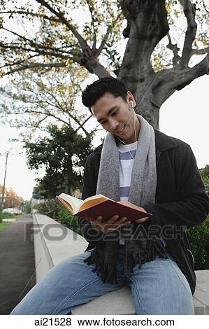 College student sitting outdoors, reading a book View Large Photo Image Stock Photo - College student sitting outdoors, reading a book. Fotosearch