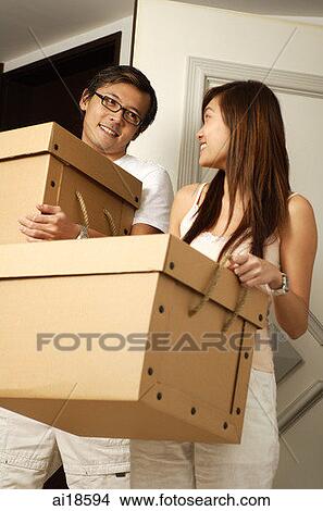 Couple at home, carrying boxes, smiling at each other View Large Photo Image Picture - Couple at home, carrying boxes, smiling at each other. Fotosearch
