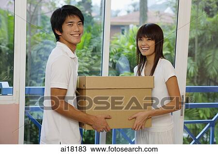 Couple carrying a box, looking at camera View Large Photo Image Stock Image - Couple carrying a box, looking at camera. Fotosearch