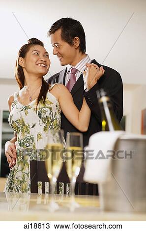 Couple embracing in background, champagne glasses in foreground View Large Photo Image Stock Image - Couple embracing in background, champagne glasses in foreground. Fotosearch