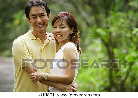 Couple embracing outdoors, looking at camera View Large Photo Image Stock Image - Couple embracing outdoors, looking at camera. Fotosearch