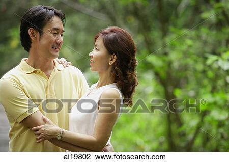 Couple embracing outdoors, looking at each other View Large Photo Image Stock Image - Couple embracing outdoors, looking at each other. Fotosearch