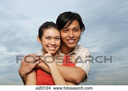 Picture - Couple embracing, smiling at camera. Fotosearch
