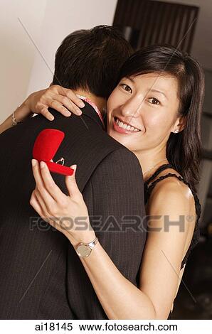 Couple embracing, woman holding box with ring, looking at camera View Large Photo Image Stock Photography - Couple embracing, woman holding box with ring, looking at camera. Fotosearch