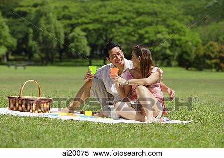 Stock Photography - Couple having a picnic, sitting side by side. Fotosearch