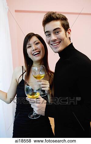 Couple holding wine glasses, standing side by side, smiling at camera View Large Photo Image Stock Photo - Couple holding wine glasses, standing side by side, smiling at camera. Fotosearch