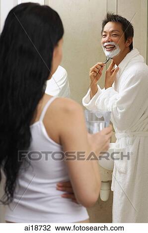 Couple in bathroom, man in robe, shaving, woman standing with glass of water View Large Photo Image Stock Image - Couple in bathroom, man in robe, shaving, woman standing with glass of water. Fotosearch