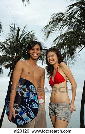 Stock Photograph - Couple in beach wear, looking at camera. Fotosearch