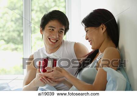 Couple in bed, man giving woman present View Large Photo Image Stock Photo - Couple in bed, man giving woman present. Fotosearch