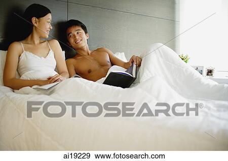 Stock Photo - Couple in bed, with book and magazine. Fotosearch