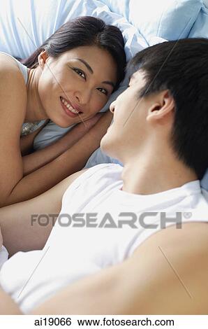 Stock Photograph - Couple in bed, woman smiling at camera. Fotosearch