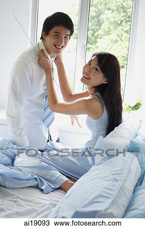 Couple in bedroom, woman adjusting man's tie, both smiling at camera View Large Photo Image Stock Image - Couple in bedroom, woman adjusting man's tie, both smiling at camera. Fotosearch