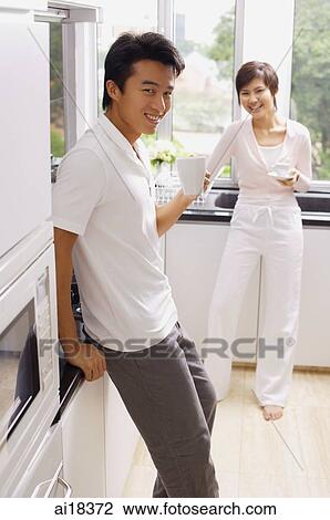 Couple in kitchen, having coffee, smiling at camera View Large Photo Image Stock Image - Couple in kitchen, having coffee, smiling at camera. Fotosearch