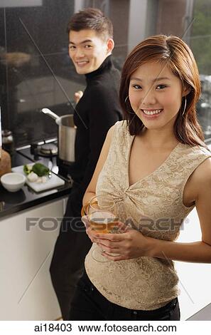 Couple in kitchen, man cooking at stove, woman holding wine glass View Large Photo Image Stock Image - Couple in kitchen, man cooking at stove, woman holding wine glass. Fotosearch