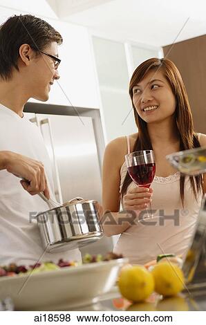 Couple in kitchen, man holding pot, woman next to him holding wine glass View Large Photo Image Stock Photo - Couple in kitchen, man holding pot, woman next to him holding wine glass. Fotosearch