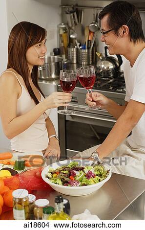 Couple in kitchen, toasting with wine glass View Large Photo Image Picture - Couple in kitchen, toasting with wine glass. Fotosearch