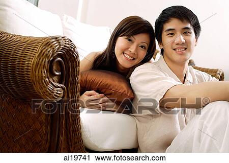 Stock Image - Couple in living room, looking at camera. Fotosearch