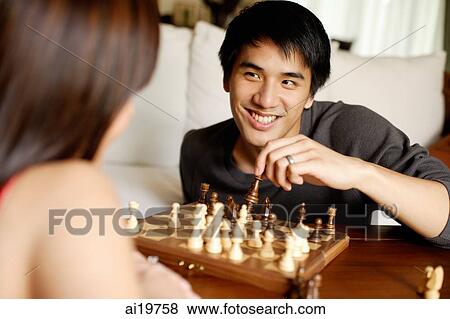 Stock Photo - Couple in living room, playing chess, man facing camera. Fotosearch