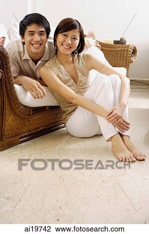 Stock Image - Couple in living room, smiling at camera. Fotosearch