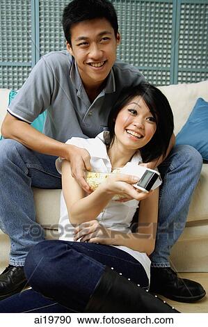 Couple in living room, woman holding remote control View Large Photo Image Stock Image - Couple in living room, woman holding remote control. Fotosearch