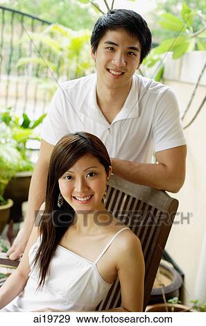 Couple in patio, woman sitting, man standing, both looking at camera View Large Photo Image Stock Photo - Couple in patio, woman sitting, man standing, both looking at camera. Fotosearch