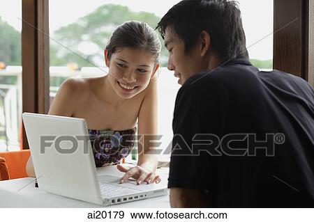 Couple in restaurant, looking at laptop View Large Photo Image Stock Photo - Couple in restaurant, looking at laptop. Fotosearch