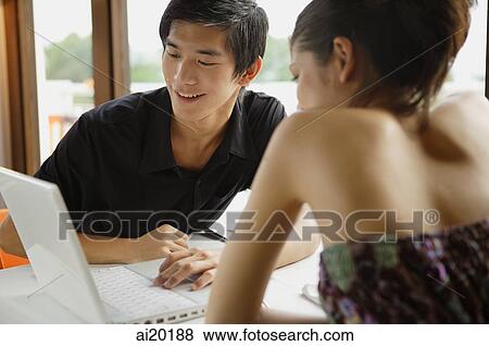 Couple in restaurant, looking at laptop View Large Photo Image Stock Photo - Couple in restaurant, looking at laptop. Fotosearch
