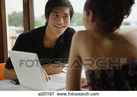 Couple in restaurant, using laptop View Large Photo Image Stock Photo - Couple in restaurant, using laptop. Fotosearch