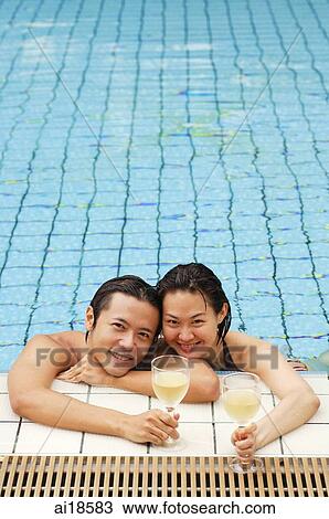 Couple in swimming pool, leaning on edge, holding wine glasses, smiling at camera View Large Photo Image Stock Image - Couple in swimming pool, leaning on edge, holding wine glasses, smiling at camera. Fotosearch