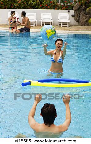 Couple in swimming pool, woman throwing ball at man, people in the background View Large Photo Image Stock Photography - Couple in swimming pool, woman throwing ball at man, people in the background. Fotosearch