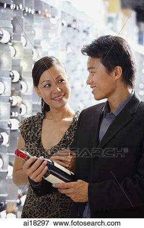 Stock Photo - Couple in wine cellar, man holding wine bottle. Fotosearch