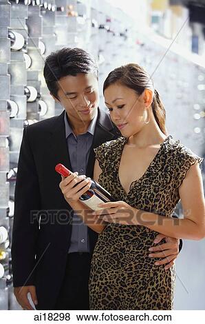Stock Photo - Couple in wine cellar, woman looking at wine bottle. Fotosearch