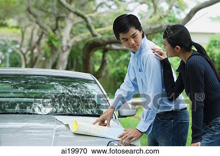 Couple looking a map on hood of car, woman with hand on man's shoulder View Large Photo Image Stock Image - Couple looking a map on hood of car, woman with hand on man's shoulder. Fotosearch