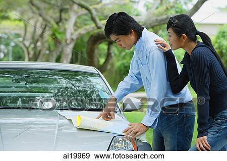 Couple looking a map on hood of car View Large Photo Image Stock Photo - Couple looking a map on hood of car. Fotosearch