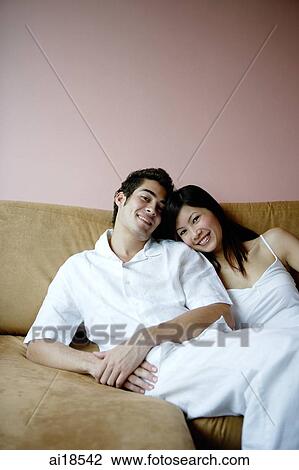 Couple lounging on sofa, looking at camera View Large Photo Image Stock Image - Couple lounging on sofa, looking at camera. Fotosearch
