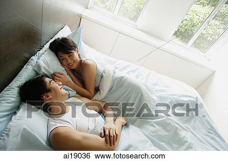 Couple lying in bed, looking at each other View Large Photo Image Stock Photograph - Couple lying in bed, looking at each other. Fotosearch